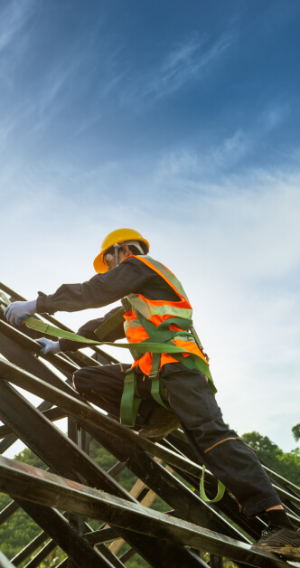 Worker on a roof with a harness, installing a wooden frame