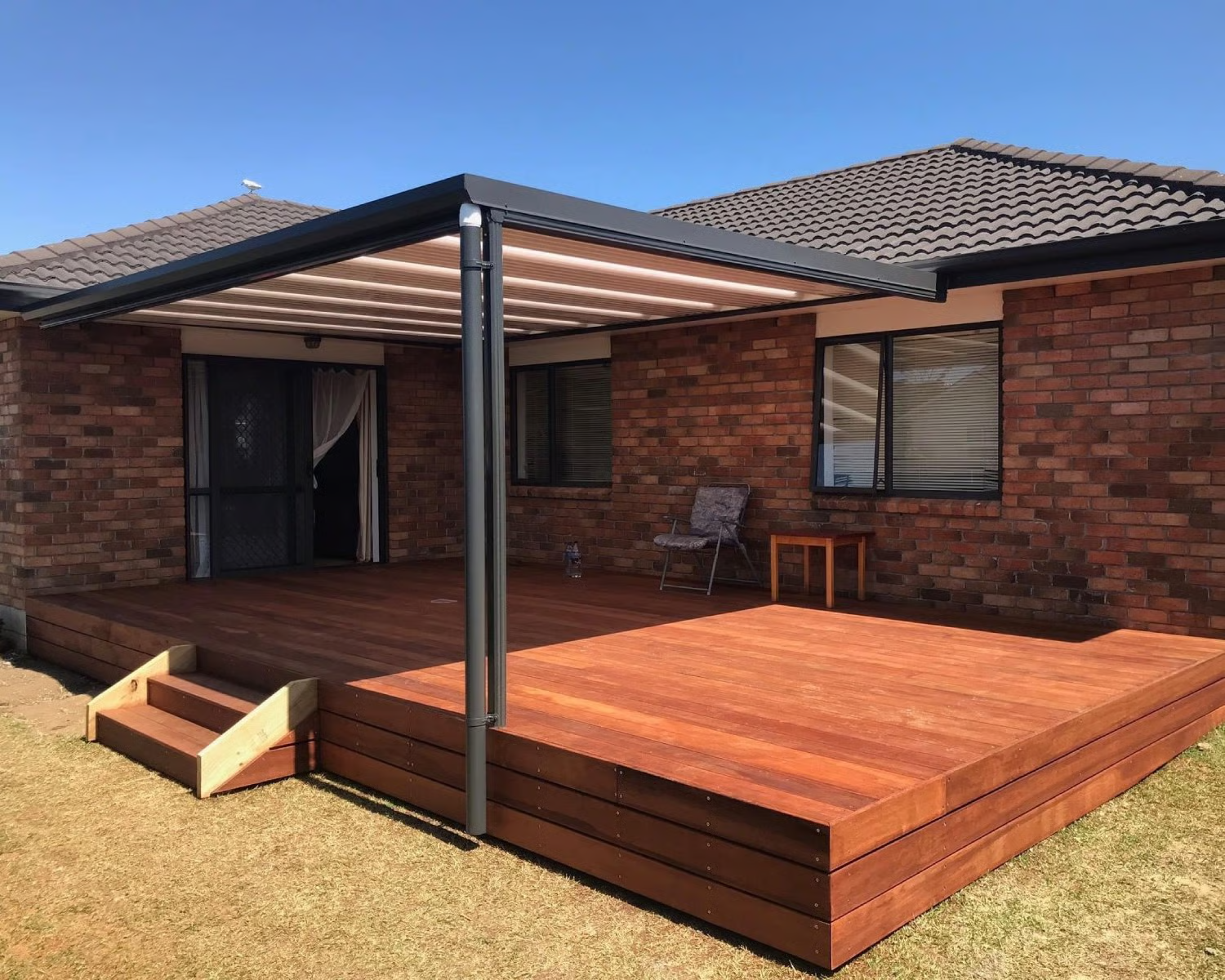 Modern pergola with louvre roof installed over wooden deck in Tauranga backyard
